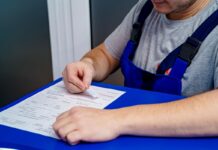 Mechanic in overalls reviewing paperwork and invoices at an office desk