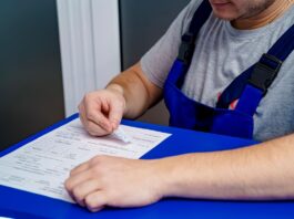 Mechanic in overalls reviewing paperwork and invoices at an office desk