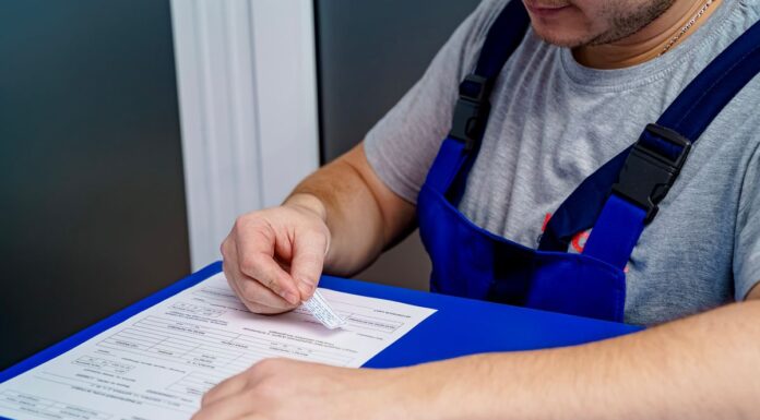 Mechanic in overalls reviewing paperwork and invoices at an office desk
